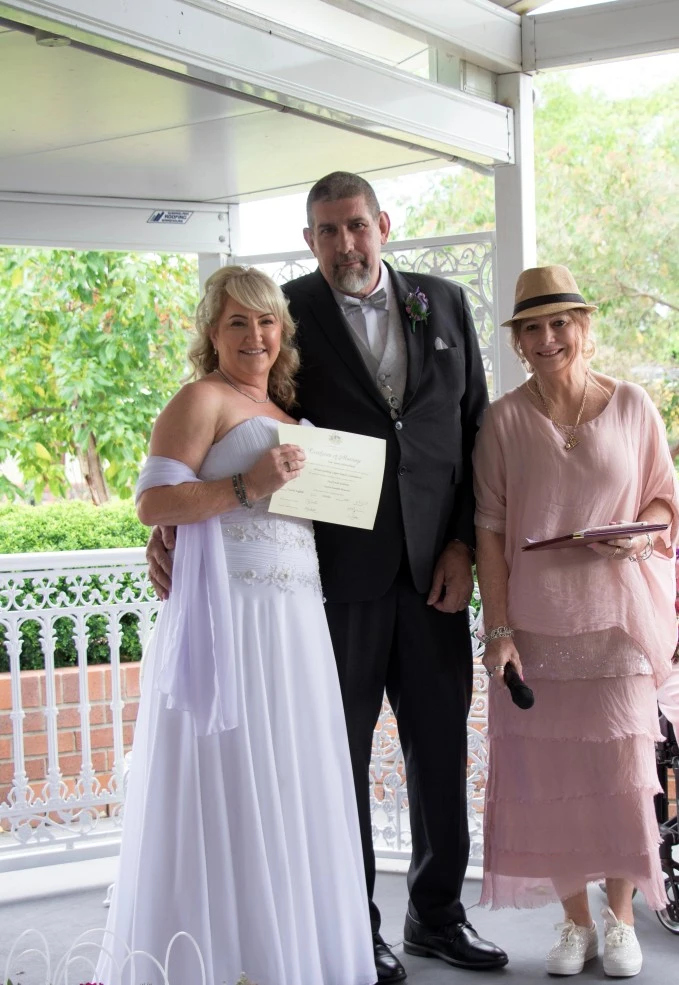 A couple smiling and the host beside them