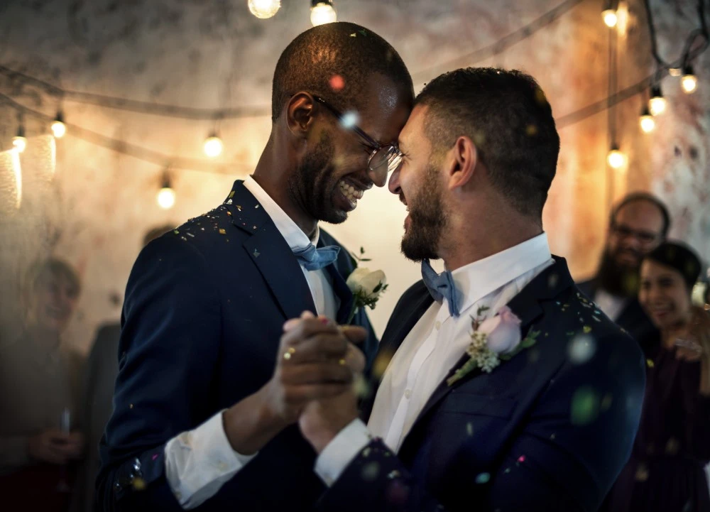 A male couple dancing and smiling during the ceremonies.